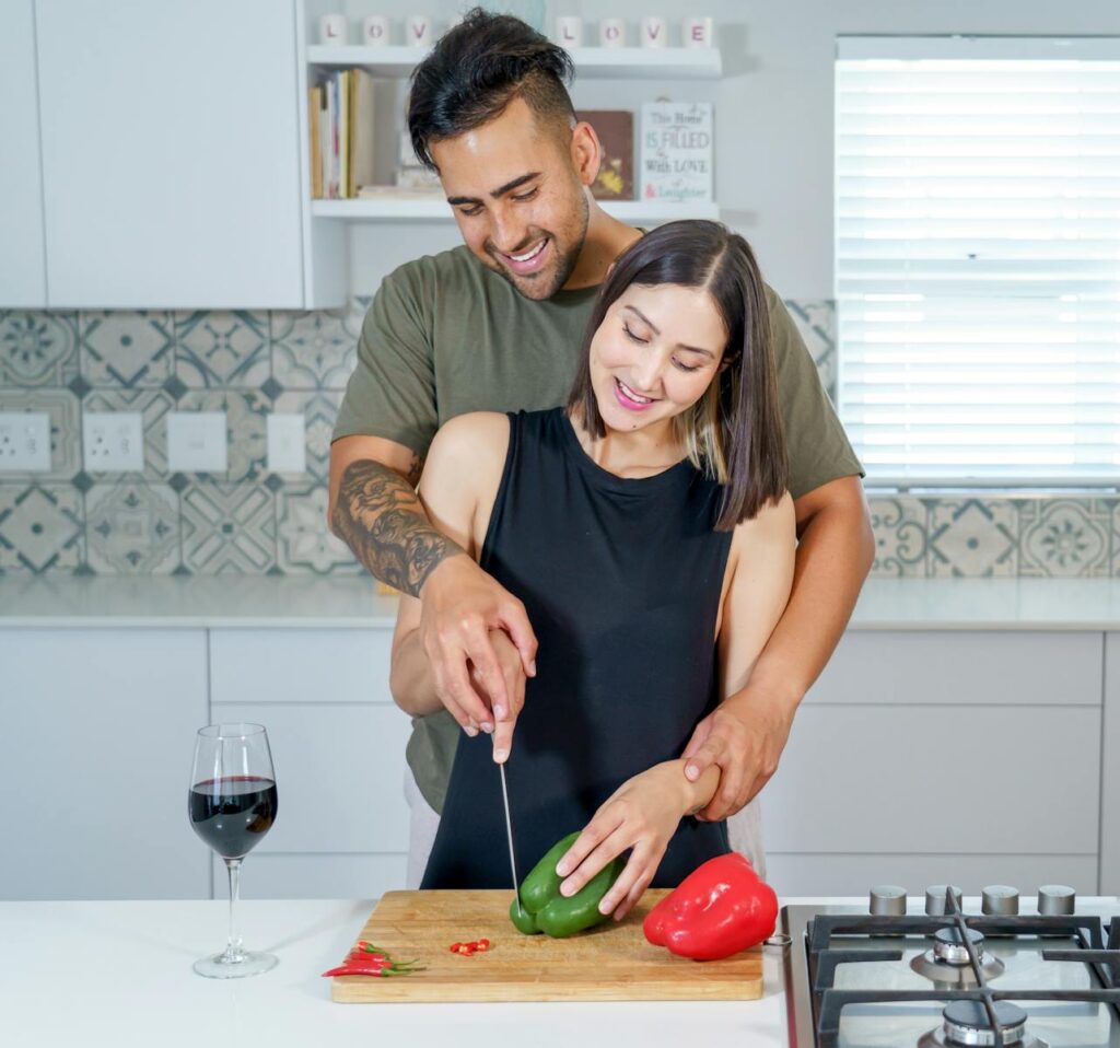Man and Woman Embracing while Cooking Together